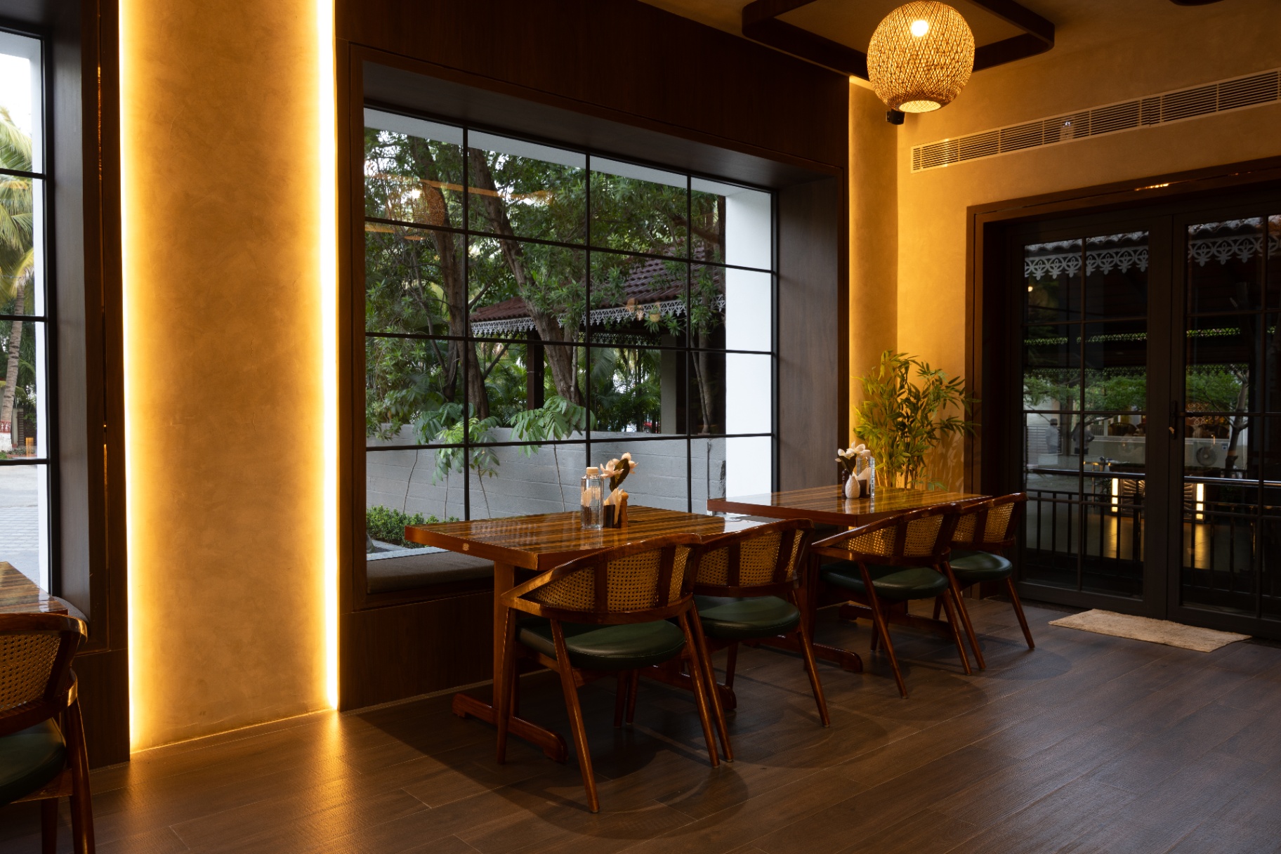 D'Scops Café warm interior seating with wooden tables, cane chairs, pendant lighting, and greenery